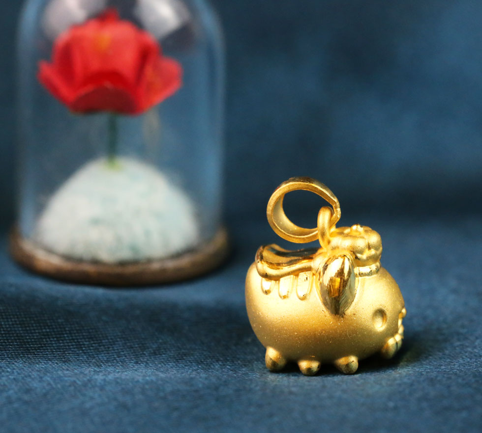 國王咖波黃金墜子情境照,貓貓蟲咖波在藍色布景中閃耀純金光澤,象徵幸福與榮耀的萌系金飾。