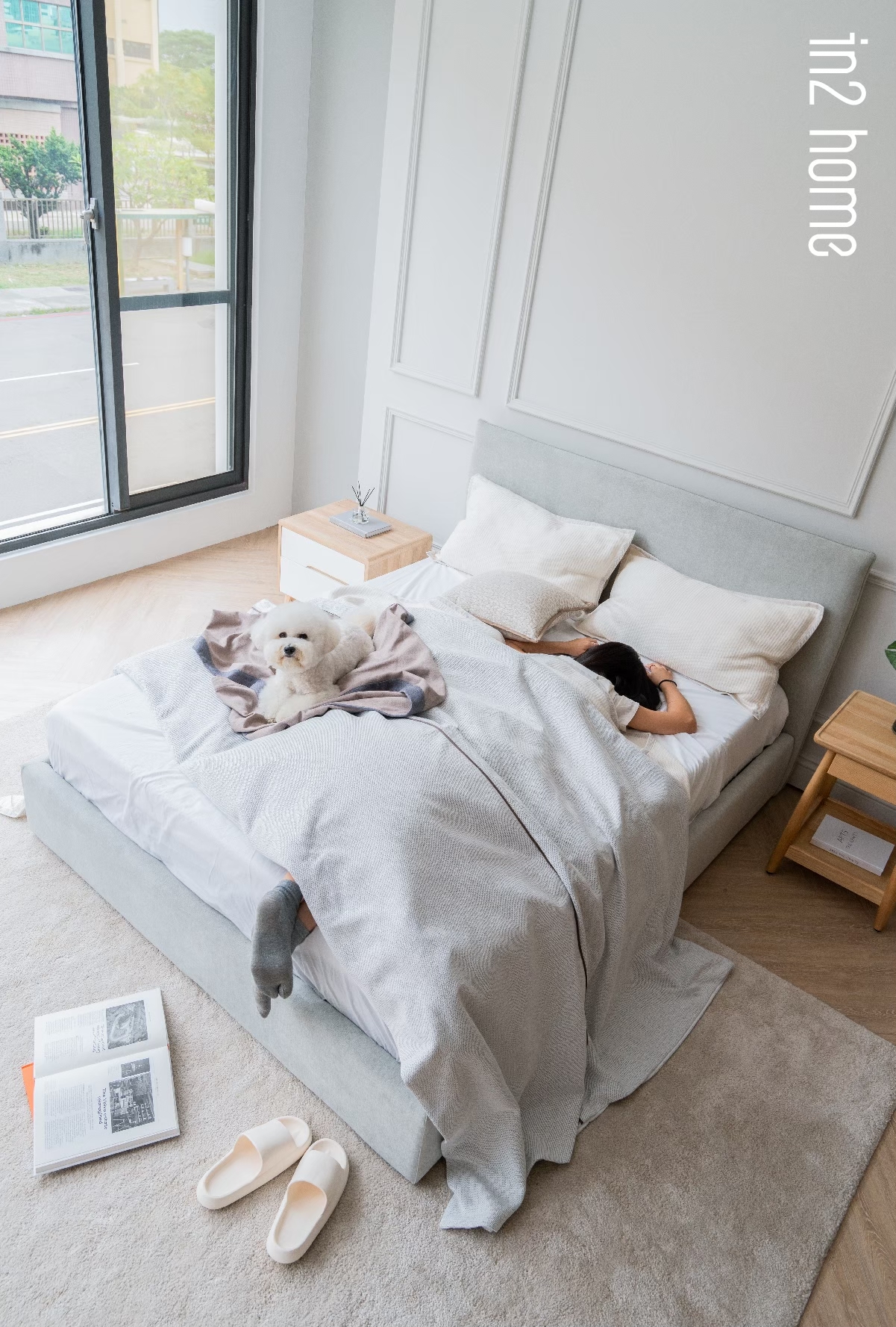 in2home小寶Bed 一個女生舒服地躺在小寶Bed上,旁邊有一隻比熊犬