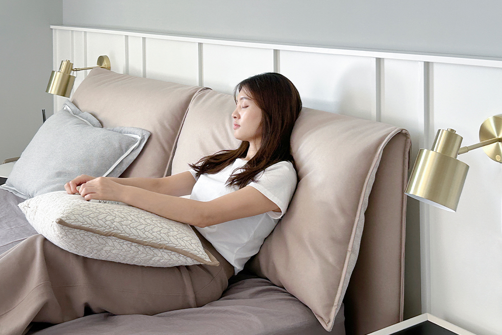 大象耳朵床板背枕設計 一個女生躺靠在大象耳朵床版背枕上
