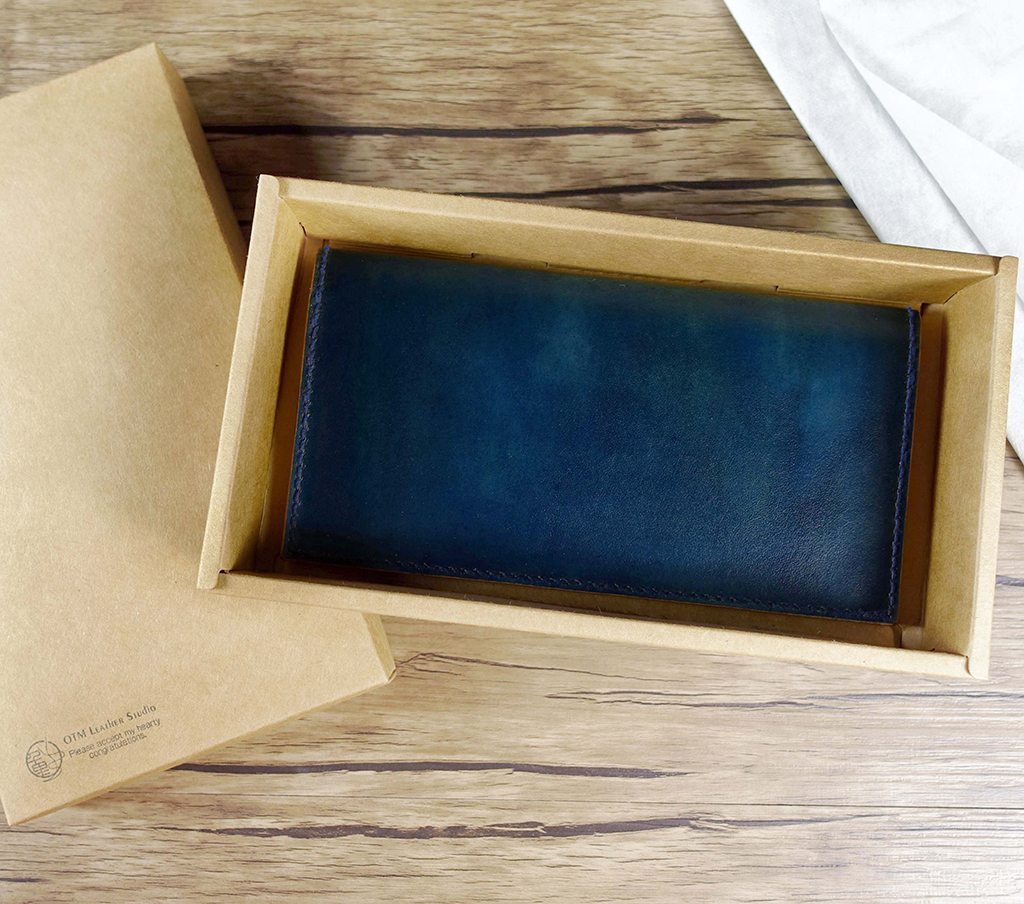 手作藍色植鞣革簡約曲線長夾外觀,平放拍攝,可見皮革自然染色與邊緣縫線細節