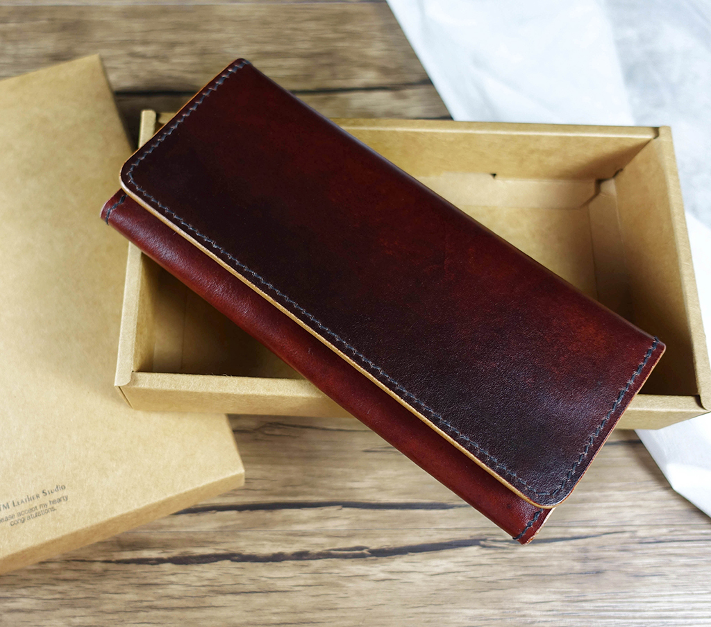 單層風琴長夾課程作品展示,翻蓋式植鞣革長夾放置於牛皮紙禮盒上,深咖啡色皮革呈現自然光澤與手縫細節