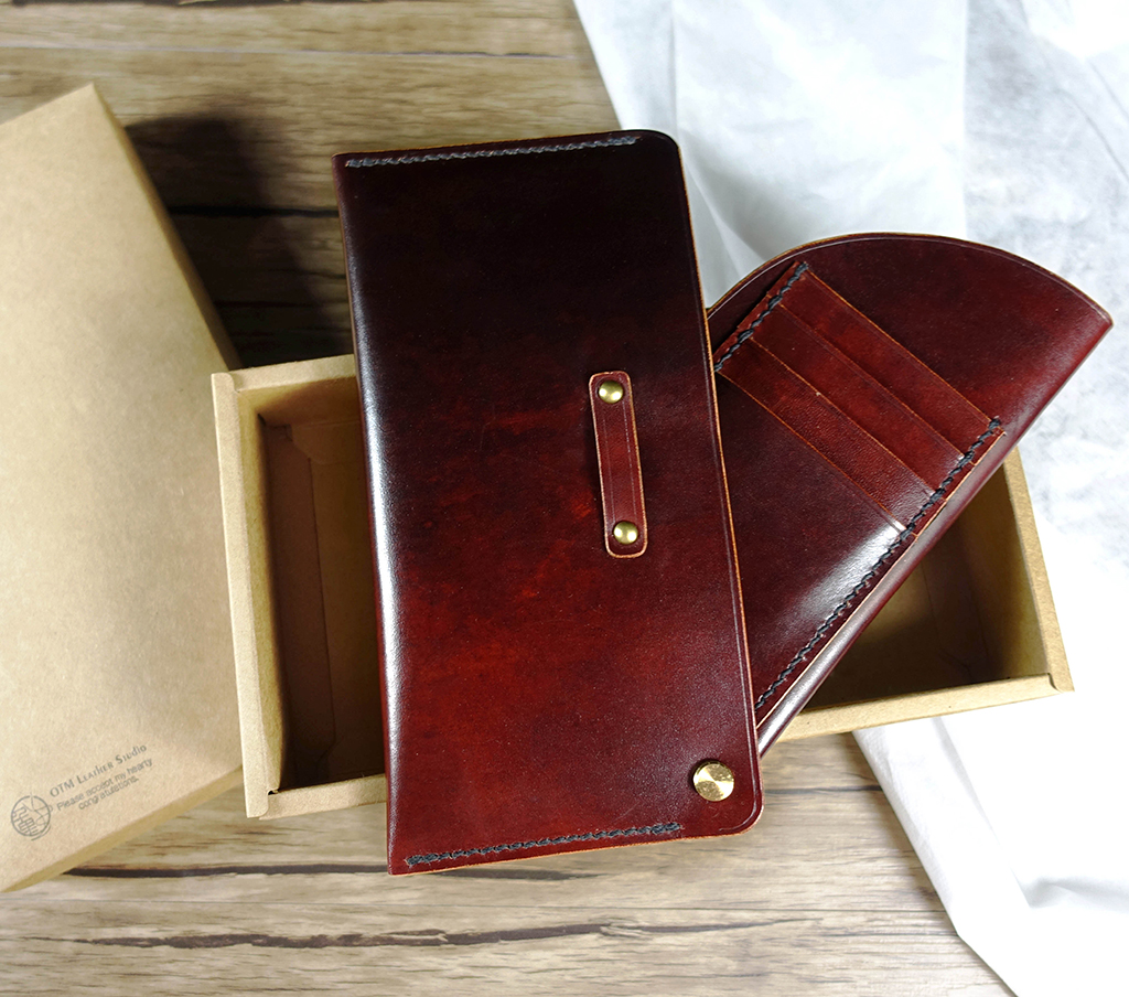 翻轉長夾課程作品展示,植鞣革紅棕色長夾置於紙盒中,內層以螺絲扣為轉軸翻轉約 90 度,呈現卡片夾層結構細節。