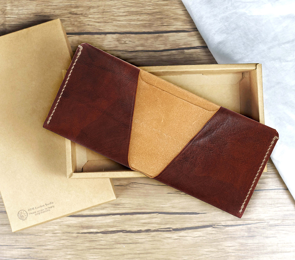 特殊單片長夾置於牛皮紙盒上方,採一片式設計,左右封邊縫線明顯,中間為原色皮革鈔票層,呈現棕色與原色對比質感。