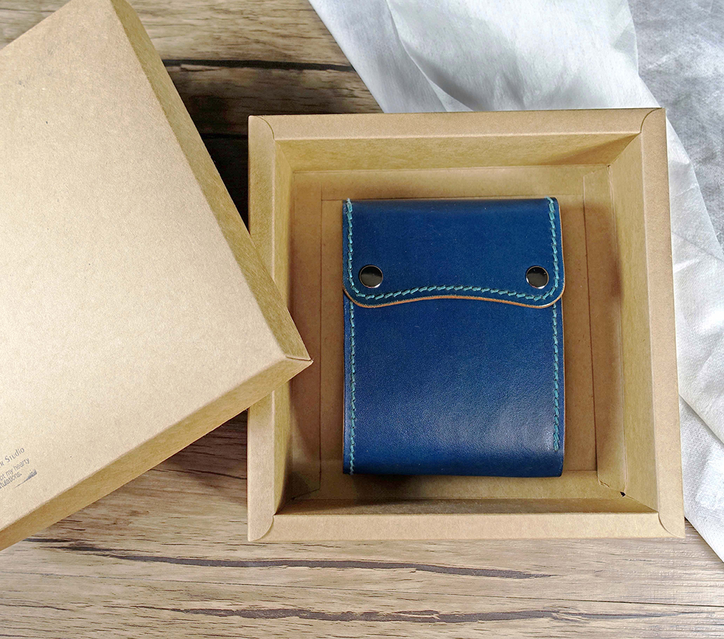 三折立體零錢包短夾課程完成作品,藍色植鞣革皮革短夾搭配弧形蓋片與金屬釦件,置於禮盒中展示,適合送禮與日常使用