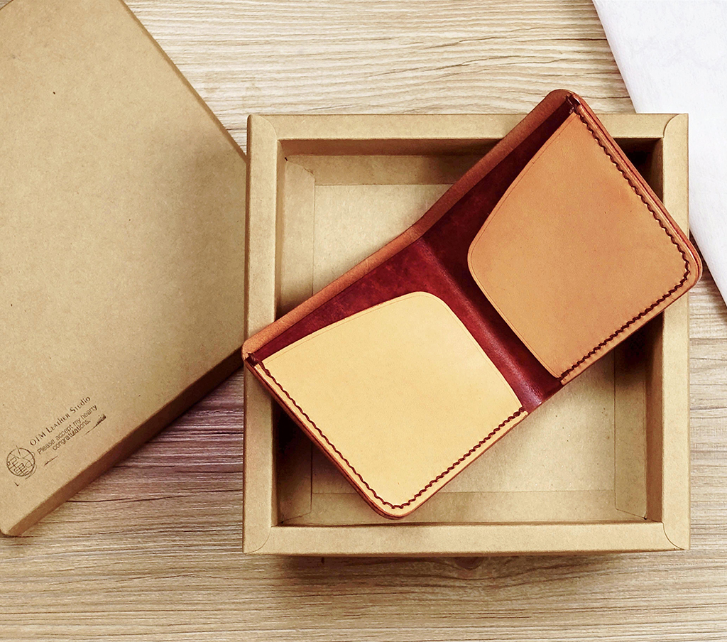 簡約短夾展開置於牛皮紙禮盒中,內部為雙面結構設計,中間鈔票層與兩側卡層清楚可見,外圈手縫細節明顯,呈現植鞣革自然色澤對比。