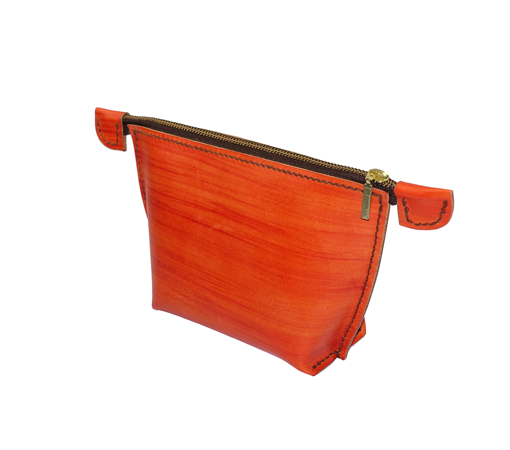 橘紅色手工染色植鞣革手拿化妝包側面視角,弧線立體包身設計,金屬拉鍊開口,黑色手縫縫線細節清晰可見。