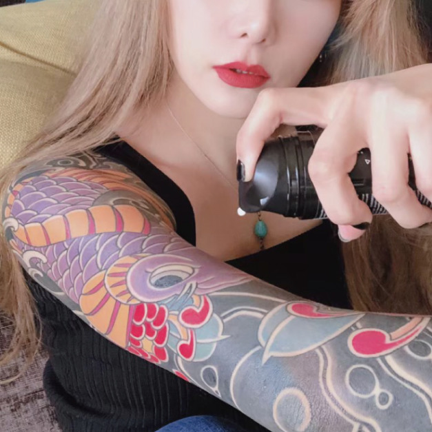 手持 INKED BY SERLANDO 刺青護色乳液的彩色手臂刺青