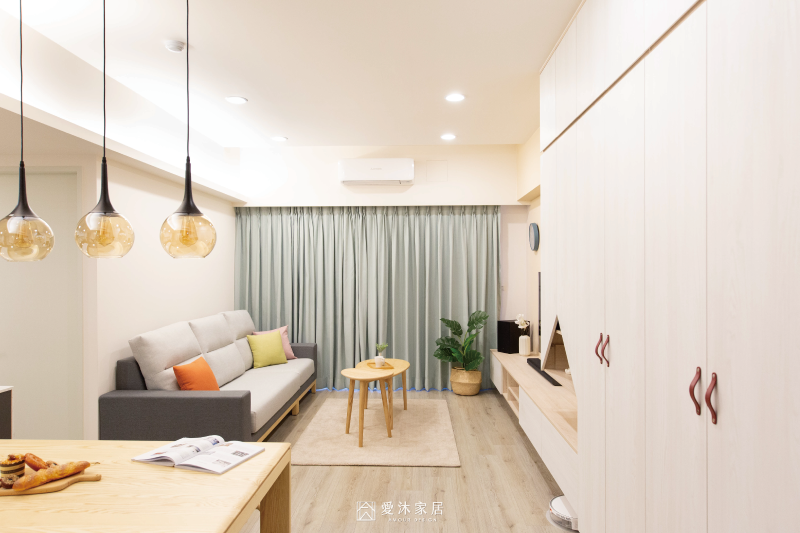 客廳設計以奶茶色跳色電視牆搭配淺木紋懸浮電視櫃，結合整面系統收納櫃，兼顧空間美感與收納機能。