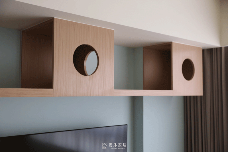客廳電視牆上方以木質層板與圓形貓洞串聯貓咪活動路徑,兼顧寵物機能與空間造型