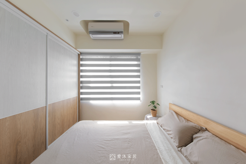 日式北歐風主臥沿牆規劃大面積系統衣櫃,以暖白與淺木色搭配營造簡約溫潤的休憩空間