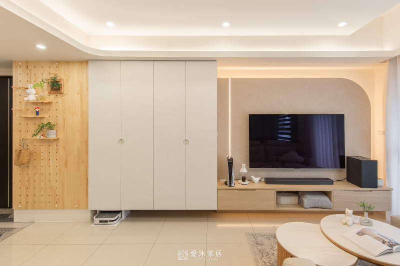 客廳系統收納櫃與弧形電視牆設計,以米白及淺木色搭配延續明亮空間感