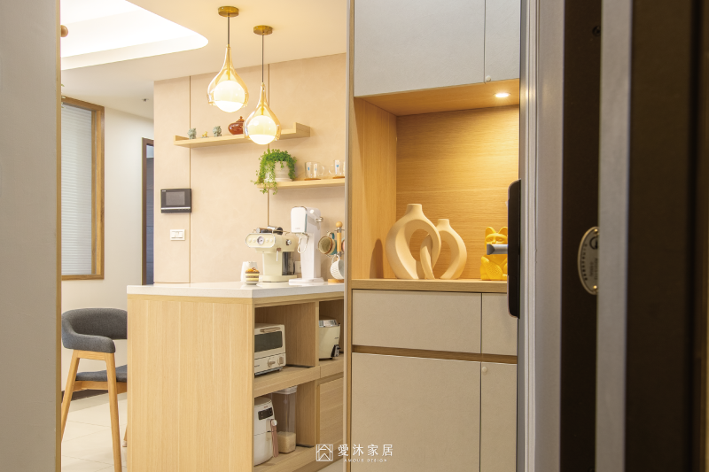 玄關望向餐廳中島與餐邊櫃，淺木色與暖色燈光營造溫馨居家氛圍
