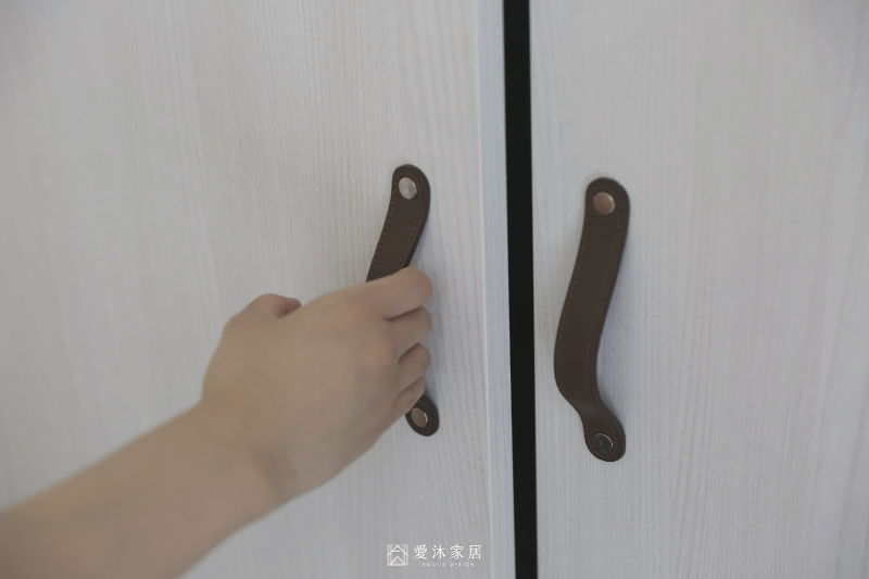 主臥白色木紋系統衣櫃搭配牛皮把手，以溫潤細節增添日式北歐風質感
