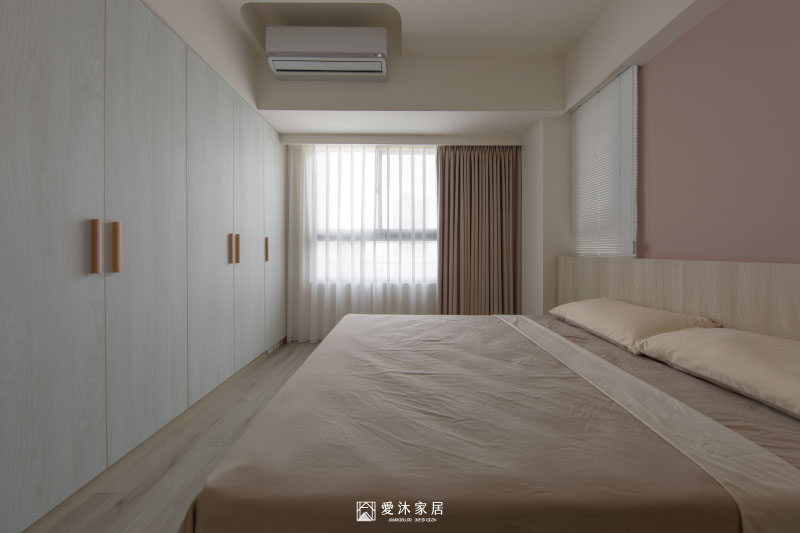 主臥整面系統衣櫃採暖白色木紋門片搭配木質把手，提供充足衣物收納並維持簡潔視覺
