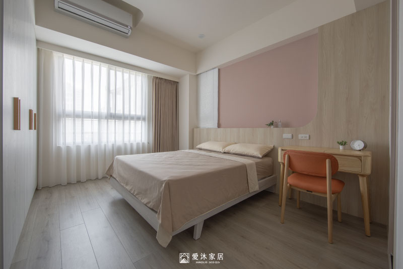 主臥設計以粉色床頭牆、圓弧造型與淺木質家具相互搭配，呈現自然柔和的休息空間