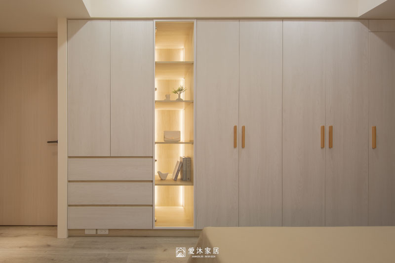主臥系統衣櫃結合玻璃展示櫃與暖色燈光，讓收納機能與生活展示自然融入臥室設計
