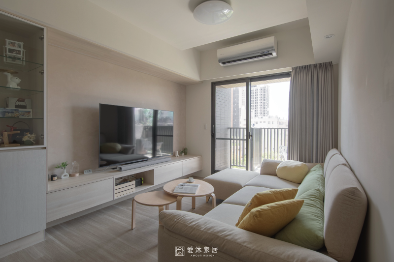 客廳以淺木色懸浮電視櫃搭配米色沙發與大面採光,營造明亮溫潤的居家氛圍