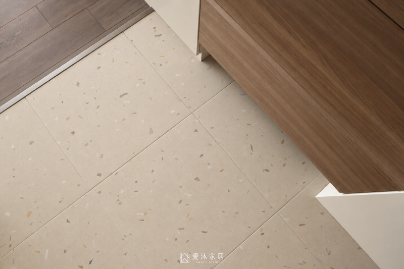玄關落塵區鋪設淺色水磨石磁磚，以材質轉換自然區分玄關與深木色室內地板