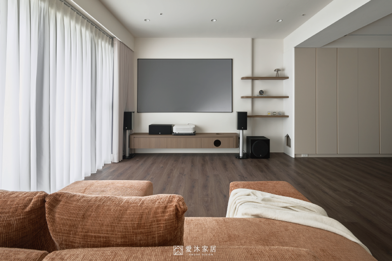 客廳電視牆以懸浮木質電視櫃整合家庭劇院設備，搭配開放層板與大面落地窗維持簡潔通透的空間感