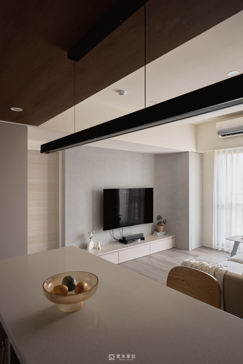 中島望向客廳的開放式空間，柔霧灰電視牆與懸浮電視櫃呈現簡潔輕盈視覺